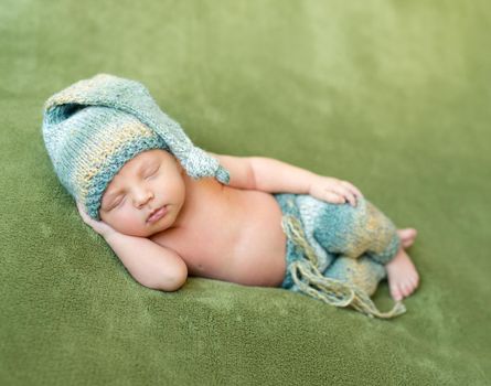 lovely newborn in hat and panties sleeps curled up