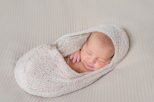 lovely sleeping infant wrapped in gray warm diaper