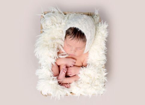 Newborn baby asleep on back with legs curled up