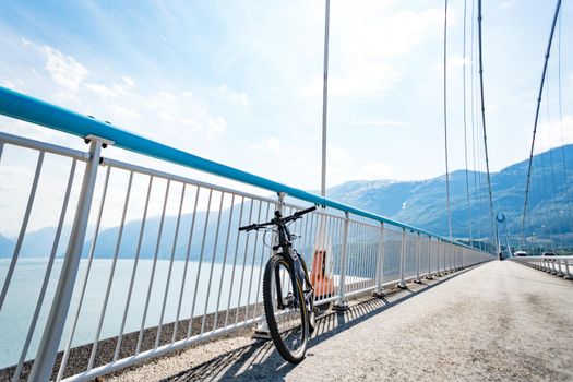 Theme of mountain biking in Scandinavia. human tourist in helmet and sportswear on bicycle in Norway on Hardanger Bridge suspension bridge thrown across the Hardanger Fjord in southwestern Norway