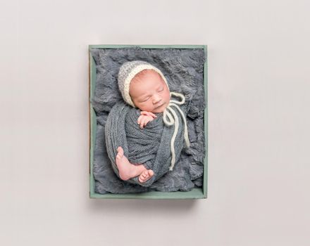 Baby wrapped in gray blanket resting, topshot