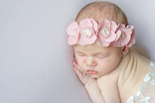 girl with pink flowers on her head napping