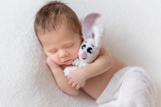 Little baby holding toy bunny and sleeping