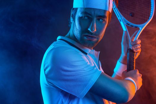Tennis player with racket in white t-shirt. Man athlete playing on dark background.