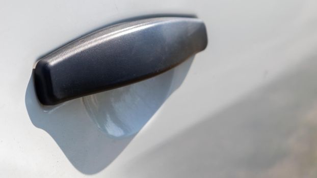 Black plastic door handle of a modern white car. Transport. Detail and part of the car. Door opening handle from outside.