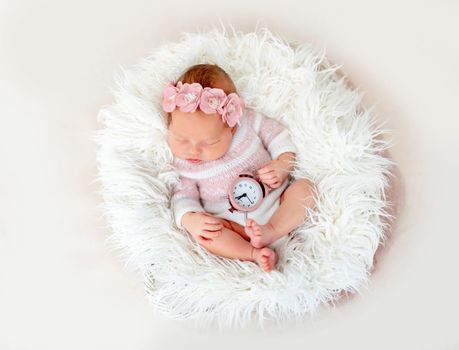 Newborn baby holding clock