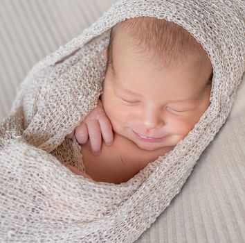 wrapped newborn baby sleeping with smile