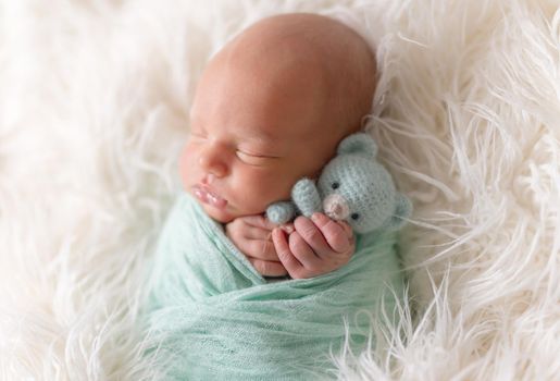 Newborn baby lying with knitted toy