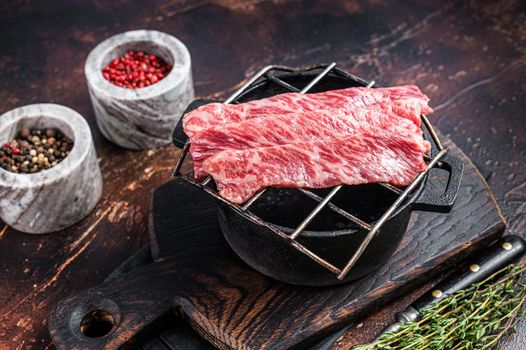 Premium raw sliced wagyu beef A5 steaks on a grill for yakiniku. Japanese foods. Dark background. Top view