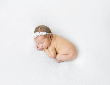 Naked infant wearing headband with flowers