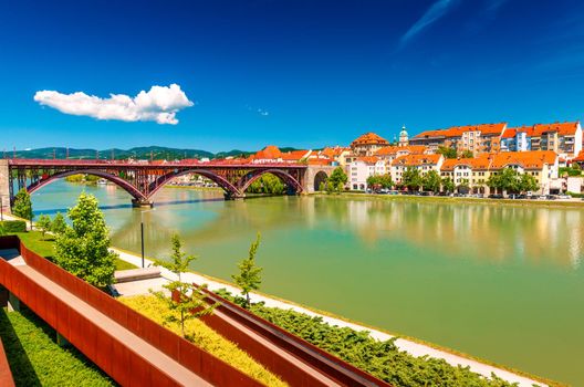 The beautiful cityscape of Maribor with the Old Bridge over the Drava River, the embankment and old buildings with orange tiled roofs