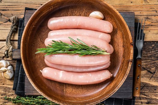 Poultry raw sausages in a wooden palte with herbs. wooden background. Top view