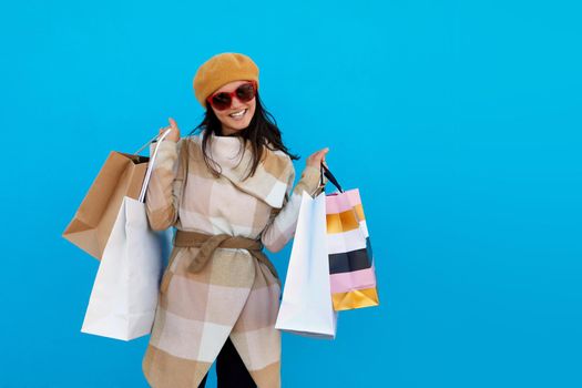 Woman coat and beret with purchases on blue background