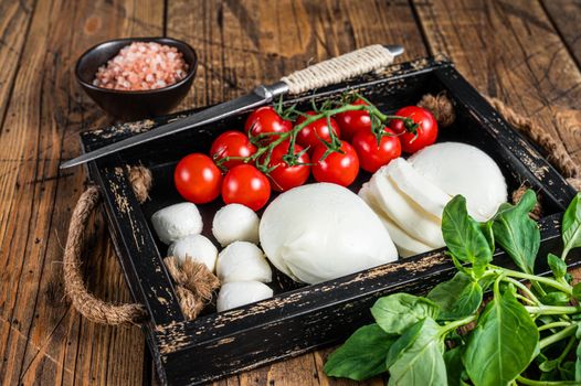 Mozzarella cheese, basil and tomato cherry in wooden tray, Caprese salad. wooden background. Top view