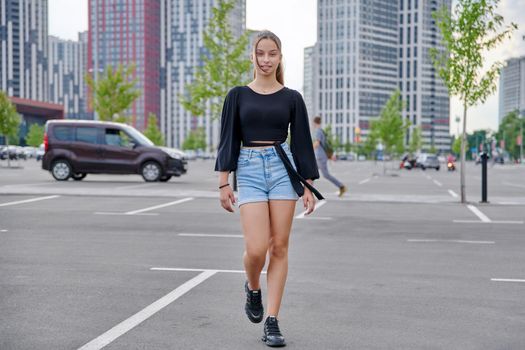 Running fashionable girl teenager, modern urban architecture parking background