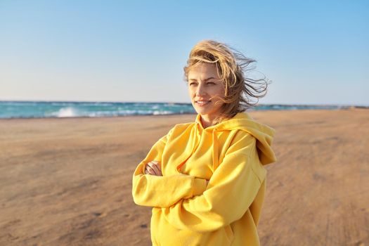 Outdoor portrait of happy woman 45 years old looking at camera with crossed arms