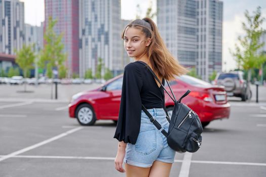 Fashionable beautiful smiling teenage girl in shorts with backpack looking at the camera