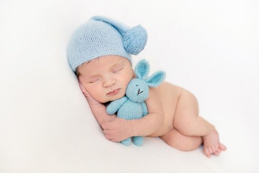 Lovely newborn baby boy hugging his plush toy