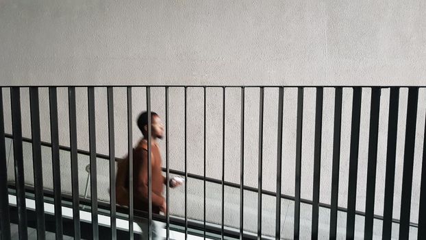 a silhouette of a black man descending the stairs down behind the metal railing.