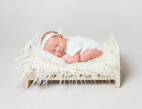 Happy baby girl sleeping on small crib