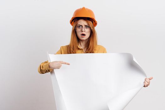 female engineer in orange hard hat blueprints architect