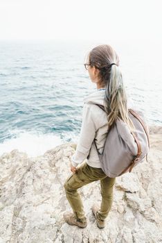 Backpacker girl standing on coastline.