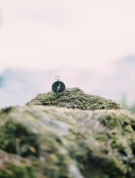 Compass on stone covered with moss.