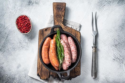 Assorted Raw sausages Chorizo and Bratwurst with spices in a pan with rosemary. White background. Top View