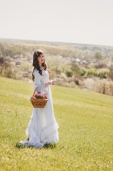 Portrait of carefree young woman in white vintage wedding style dress in spring cherry blossom garden valley