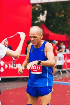 POLTAVA, UKRAINE - 1 SEPTEMBER 2019: A mature seniour man reaches finish line during Nova Poshta Poltava Half Marathon