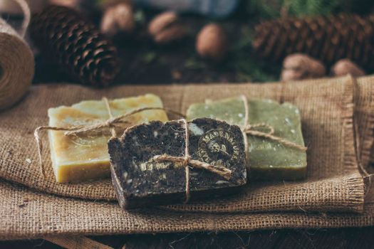 Pieces of beautiful natural handcrafted soap on wooden background with botanical elements, close up view.