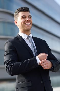 Young businessman near a office building wearing black suit