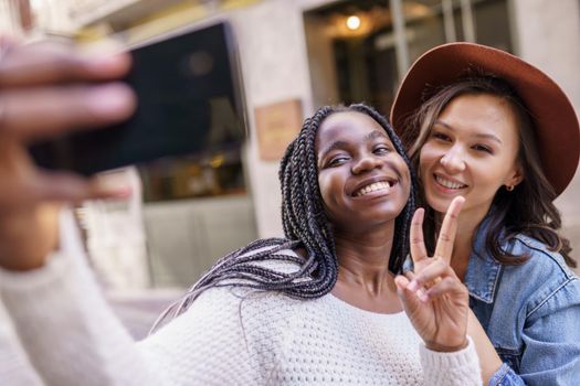 Two beautiful multiethnic women making selfie and grimacing