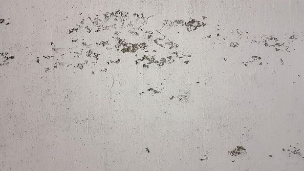 old shabby wall with cracks and chips with whitewash and exfoliated plaster, putty. Vintage gray textured putty on the wall. Rough grunge wall background.