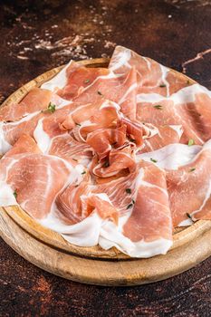 Prosciutto crudo ham on a wooden board. Dark background. Top View