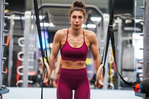 Athletic woman doing some pull up exercises in the gymnastic rings