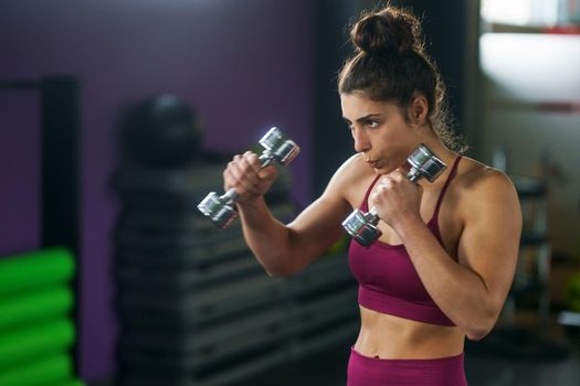 Sporty woman punching and boxing with dumbbells.