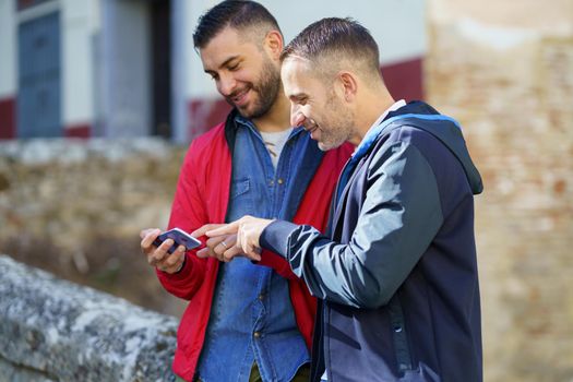 Gay couple looking at their smartphone outdoors