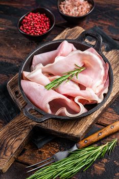 Prosciutto ham sliced in a pan. Dark wooden background. Top view
