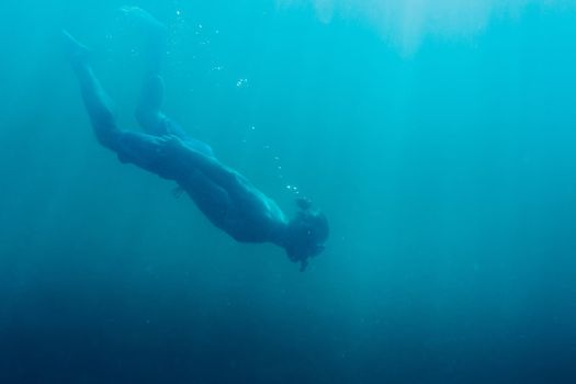 Young man free diver swimming in deep sea.
