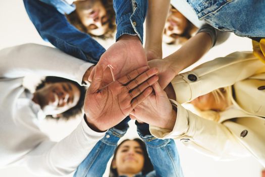 Hands of a multi-ethnic group of friends joined together as a sign of support and teamwork.