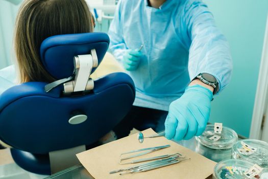 a dentist wearing gloves in the dental office holds a tool before working