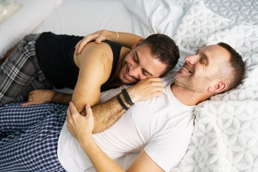 Gay couple hugging together on their bed.