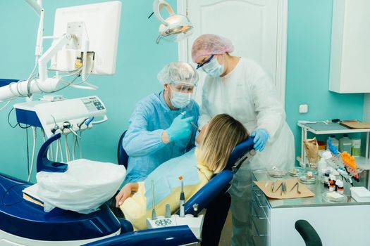 a dentist in a protective mask colitis painkillers in the dental office with an assistant