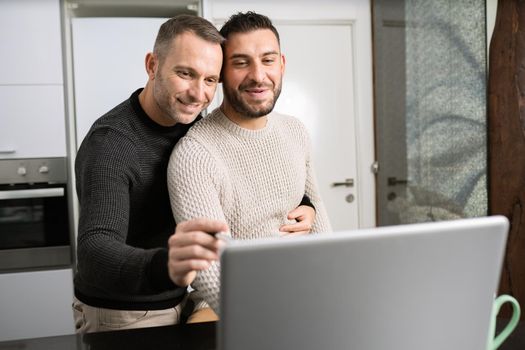 Romantic Gay couple working together at home with their laptops.
