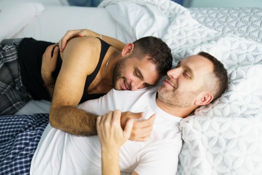 Gay couple hugging together on their bed.