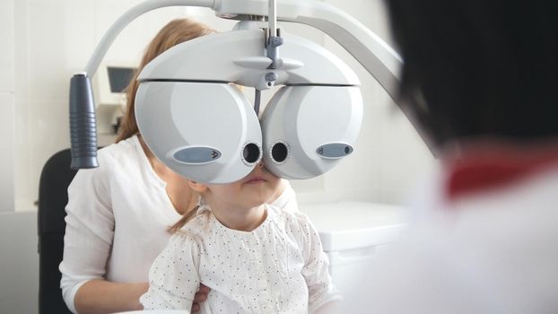 Children ophthalmology - optometrist Checks Eye of little girl