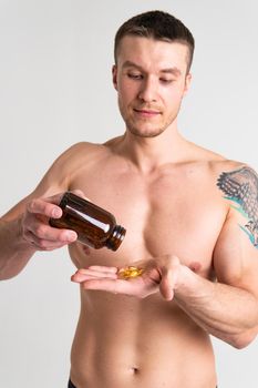Fish oil is eaten by a man in the hands of vials and a glass bottle fish health vitamin, treatment tablet healthcare lifestyle, gel People smile fat, background female giving dieting