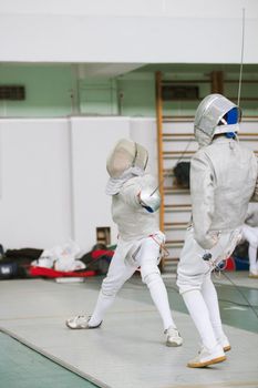 Two young fencers fighting on the fencing competition