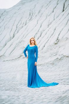 blonde girl in a blue dress with blue eyes in a granite quarry